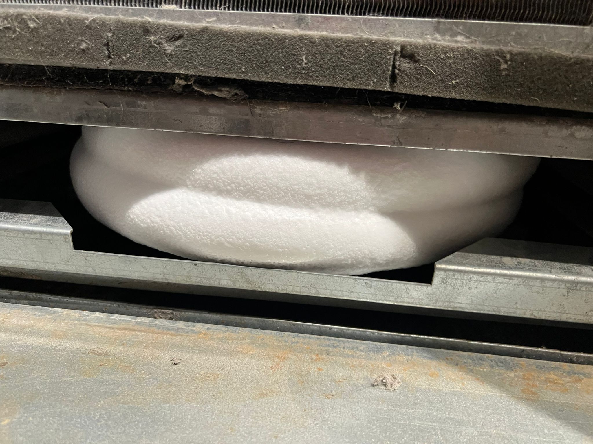 Heavy ice buildup beneath a condo heat pump coil, relevant to Toronto water leak diagnosis